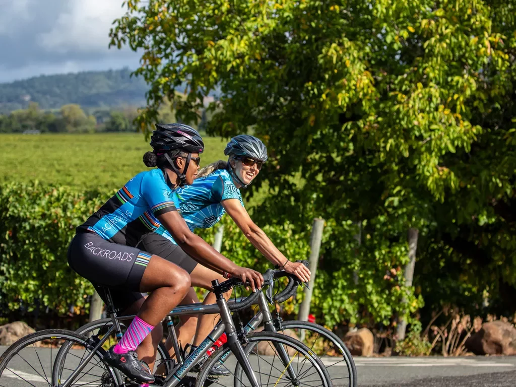 Two guests cycling past vineyard.