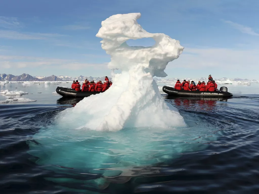 Riding in a zodiac boat past a large iceberg