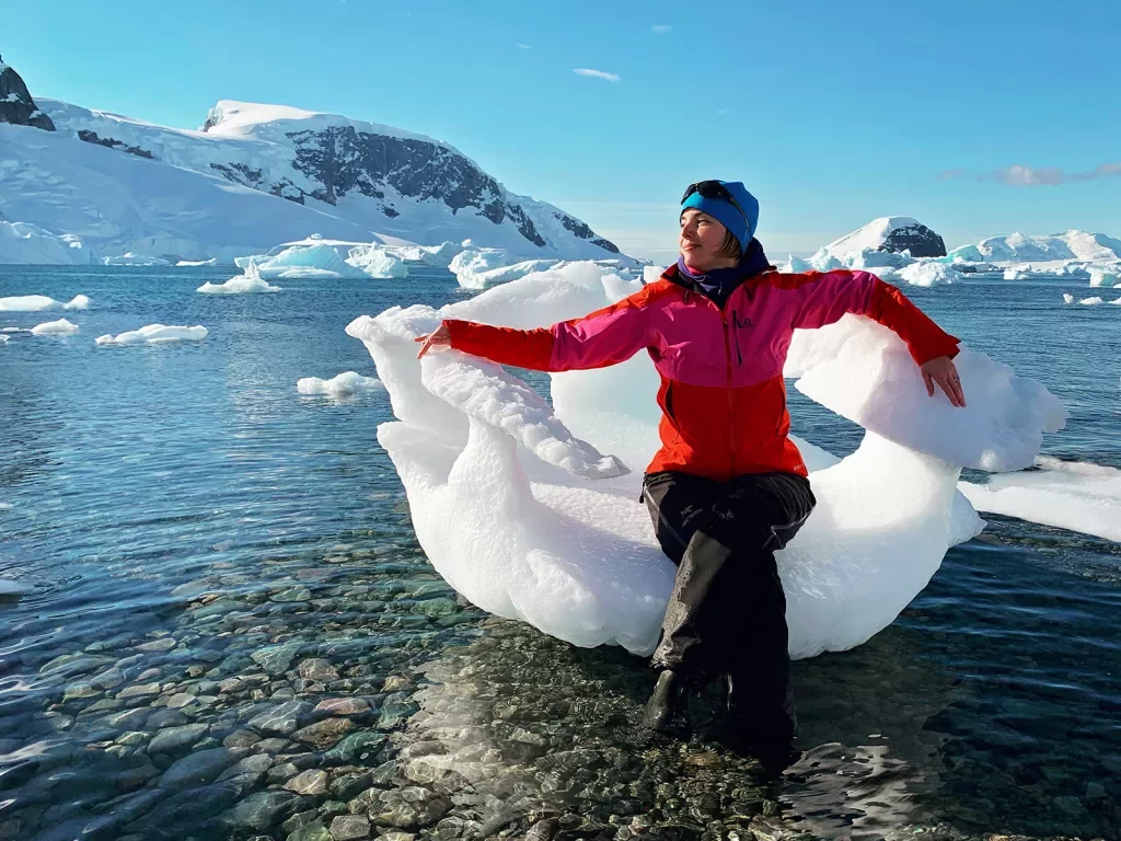 Woman sitting in a large piece of ice in Antarctica