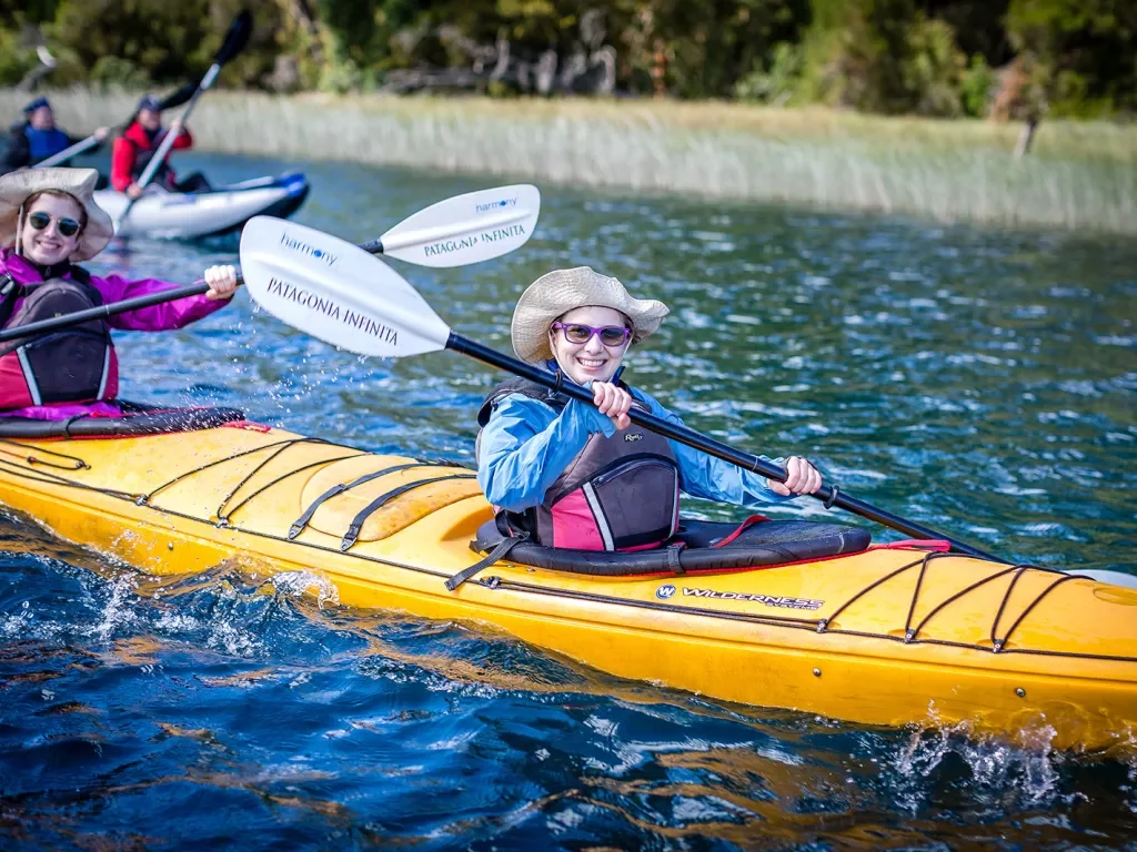 Four guests in kayaks, smiling at camera.