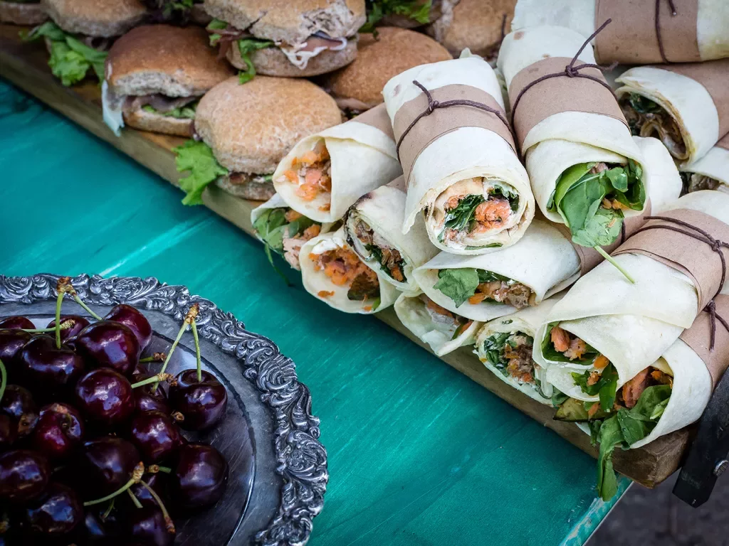 Platter of sandwiches and wraps, cherries.