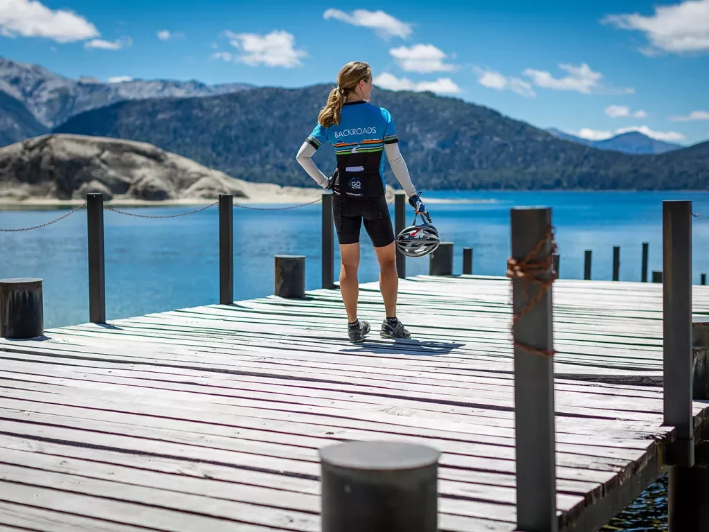 Guest in bike gear on pier, overlooking mountains, lake.