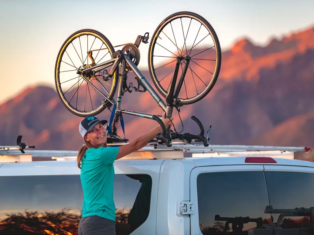 Guide smiling at camera mounting bike on van in arizona
