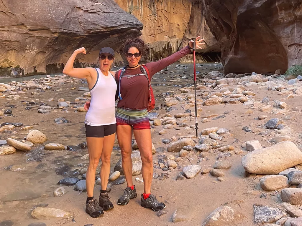 Female hikers in canyon narrows: arms out, guns out