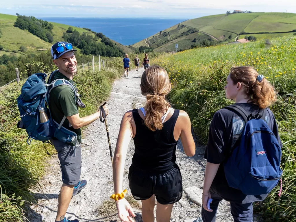 Group of guests walking towards French coast, large hills on either side.