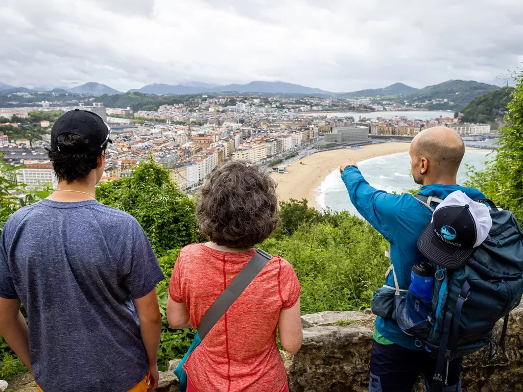 Two guests & leader overlooking French coastal town, leader pointing to something.