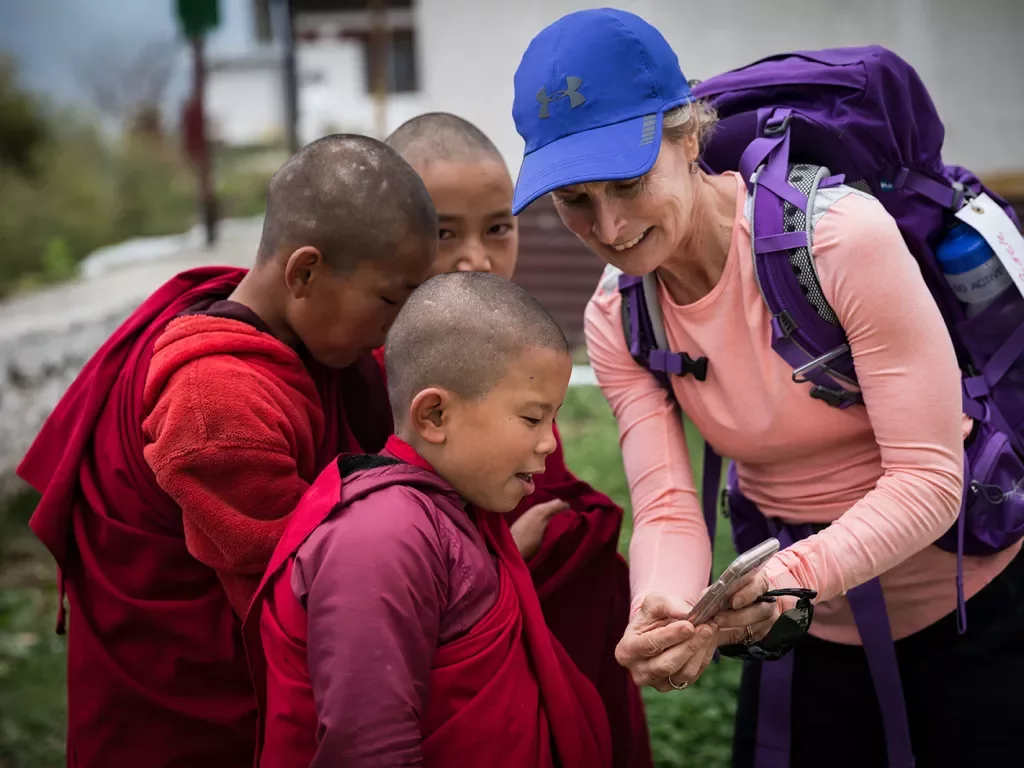 Woman showing her phone to young monks in Bhutan