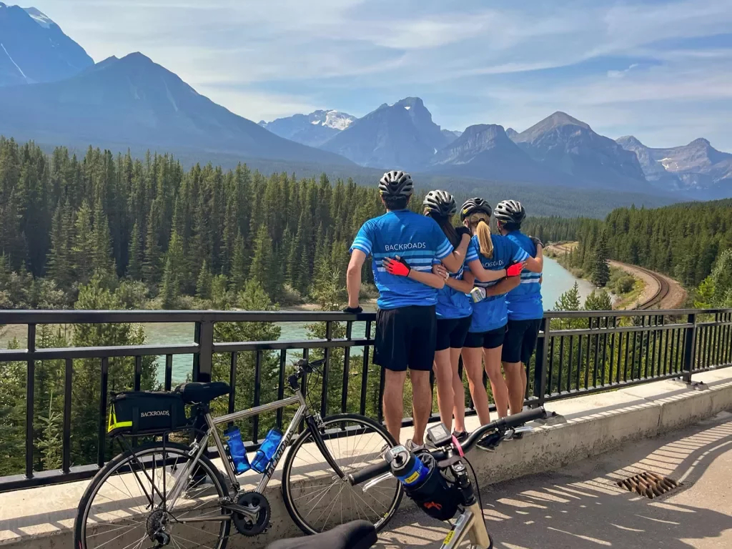 Four guests looking towards forest and mountains, bikes beside them.