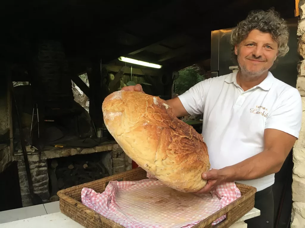 Local bake holding large loaf of bread.