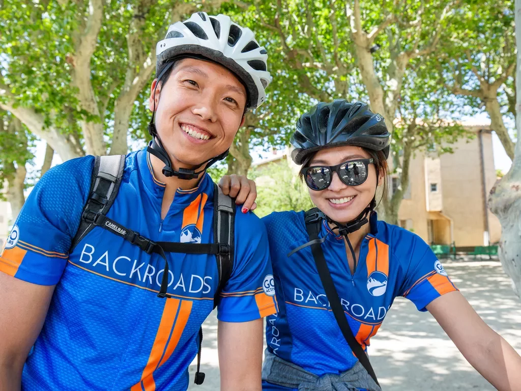 Two Backroads guests wearing bike jerseys and smiling at the camera
