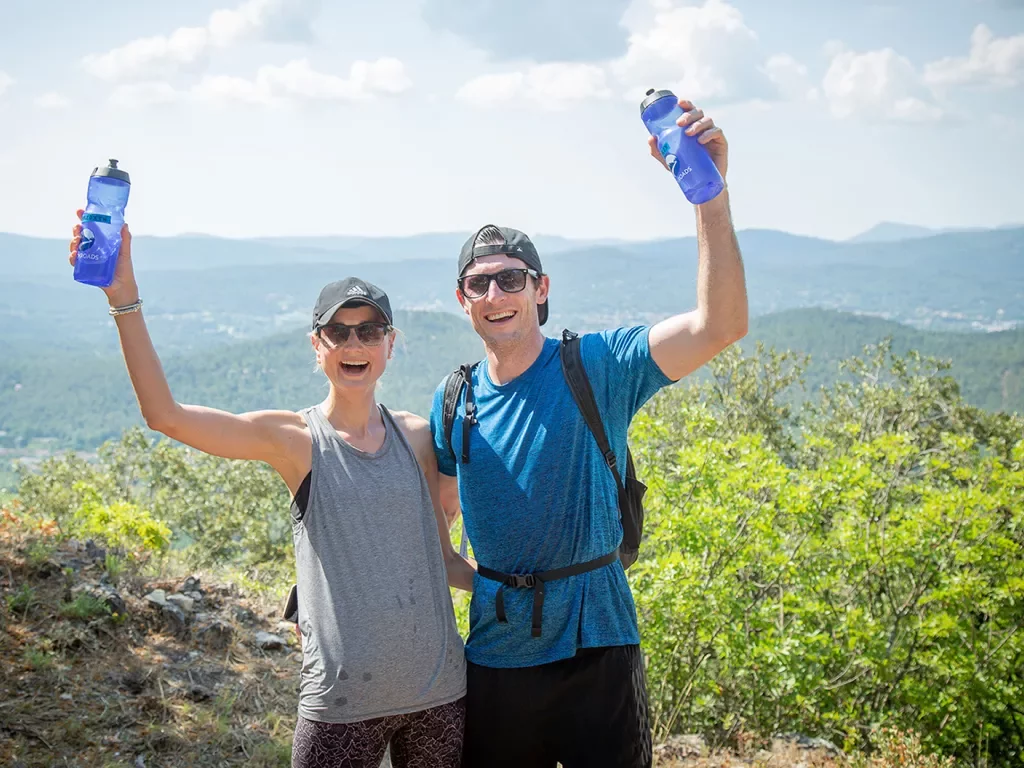 Two guests wearing hiking clothes and holding blue water bottles