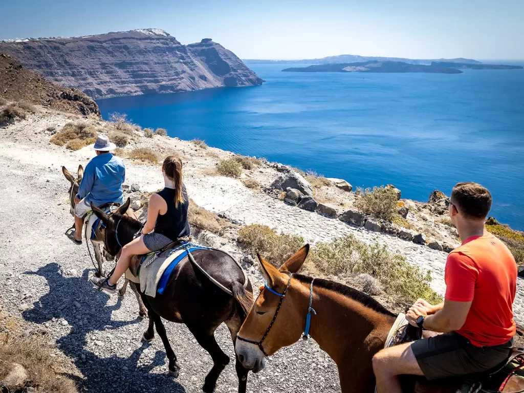 Three guests on horseback, walking along coastline.