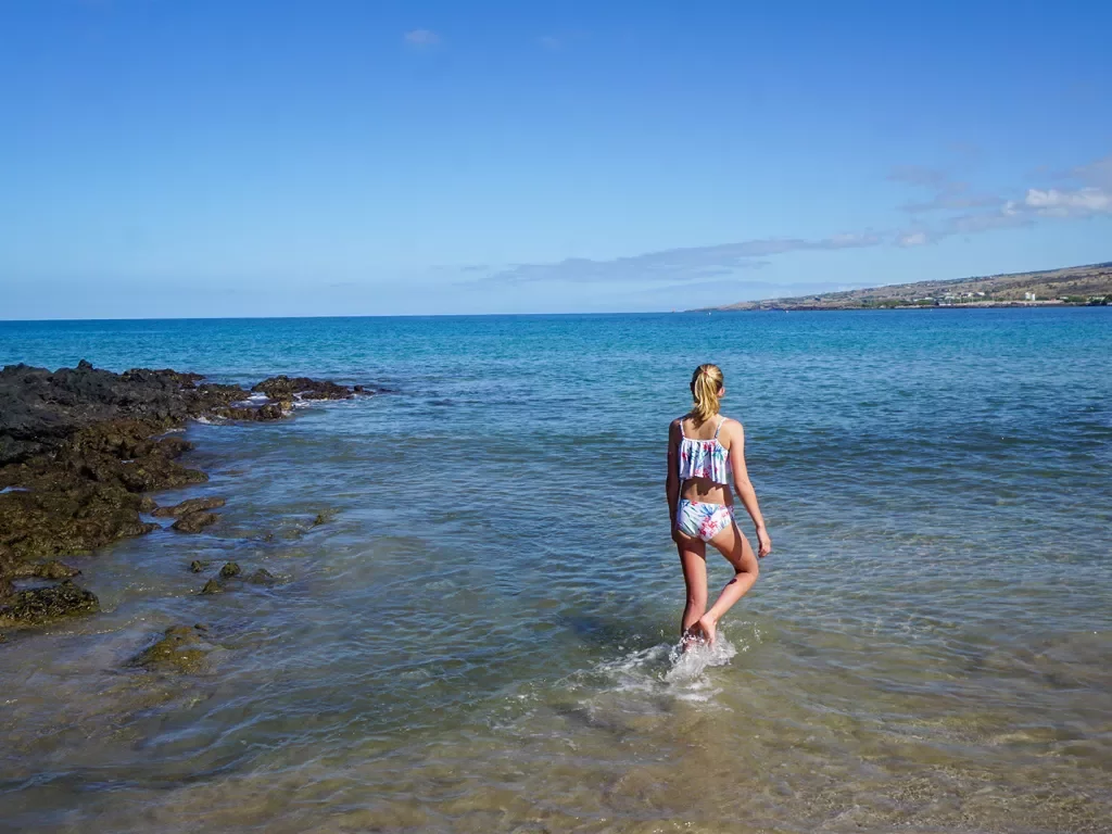 Woman walking in the ocean by the beach in Hawaii