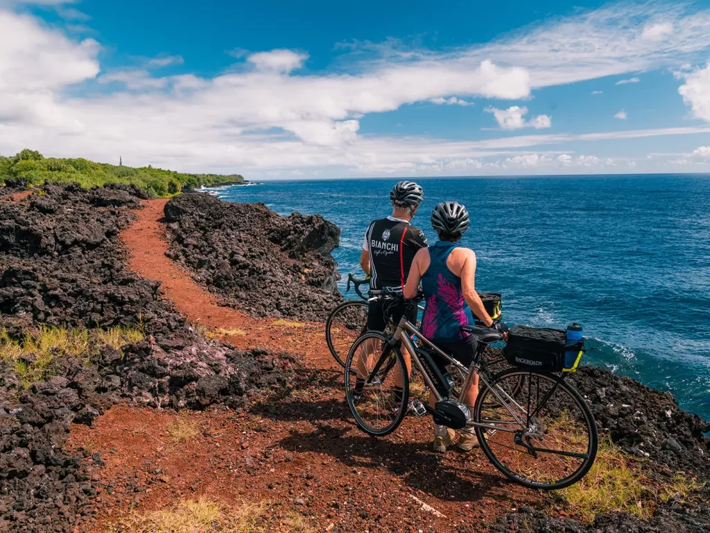 Two bikers taking a break and looking out at the ocean in Hawaii