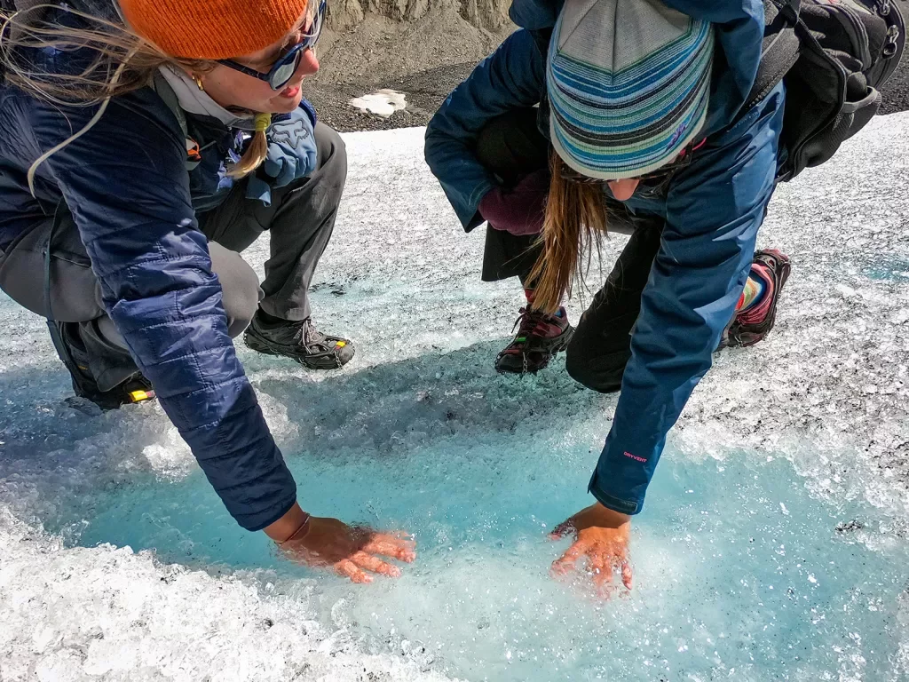 Two guests with their hands in a small ice pool.