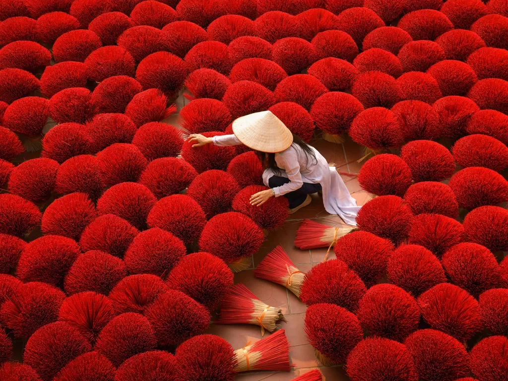 Person among bright red bundles of incense