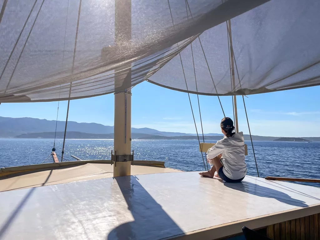 Shot of guest on sailboat, overlooking ocean, sun.