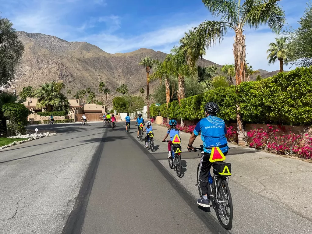 Group of guests riding single-file through a desert neighborhood.