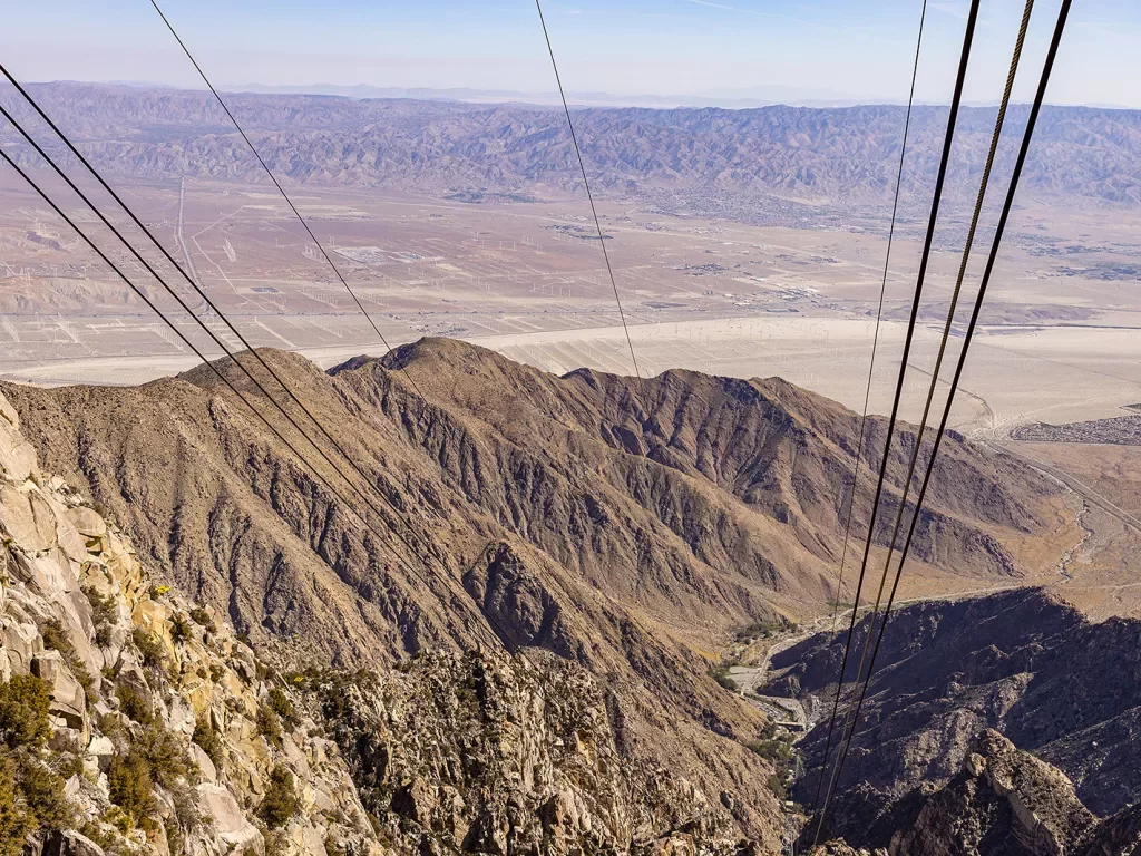 Wide shot of desert landscape, cables/wires in foreground.