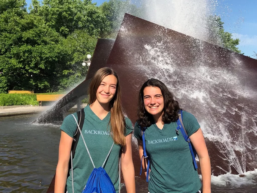 Two young guests smiling in front of a water sculpture.