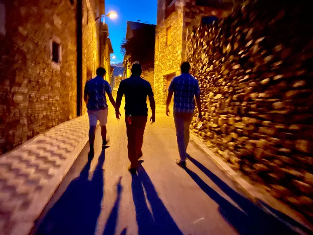 Three people walking down a charming alley at night