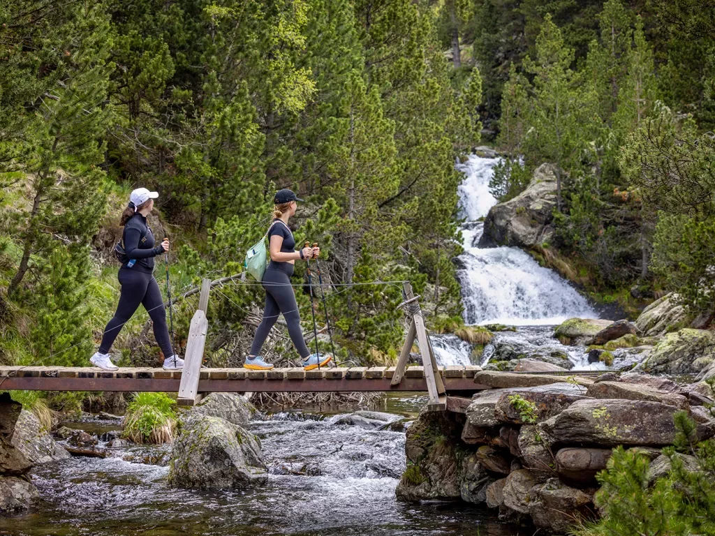 Hiking across a bridge with a waterfall in the background