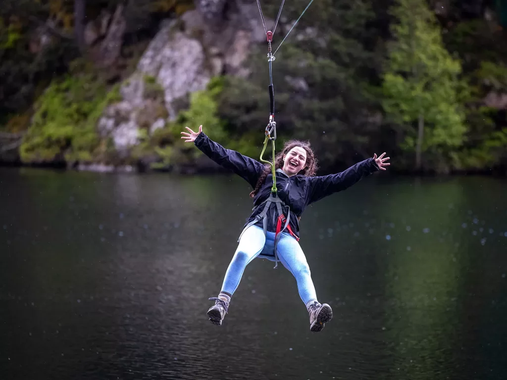 Woman zip-lining over a lake