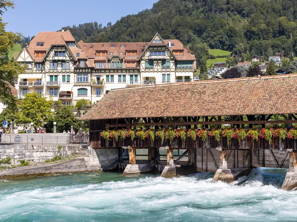 Bridge over the Aare River in Thun, Swiz. Large German style house in background.