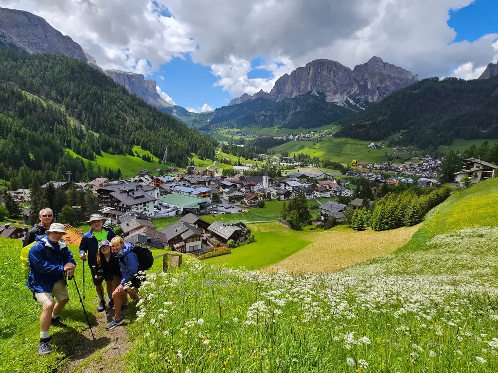 Five guests posing for camera, Dolomites valley town in distance.