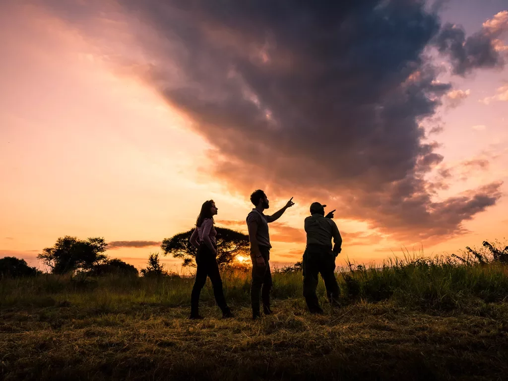 Three travelers looking off camera with African sunset in the background