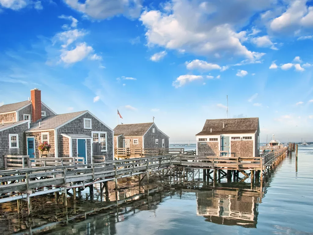 Shot of three small houses on the water, pier and small boat in background.