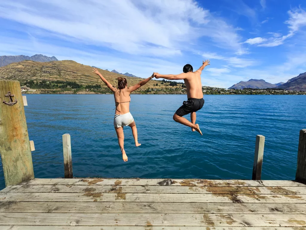 Two people jumping into a lake in New Zealand
