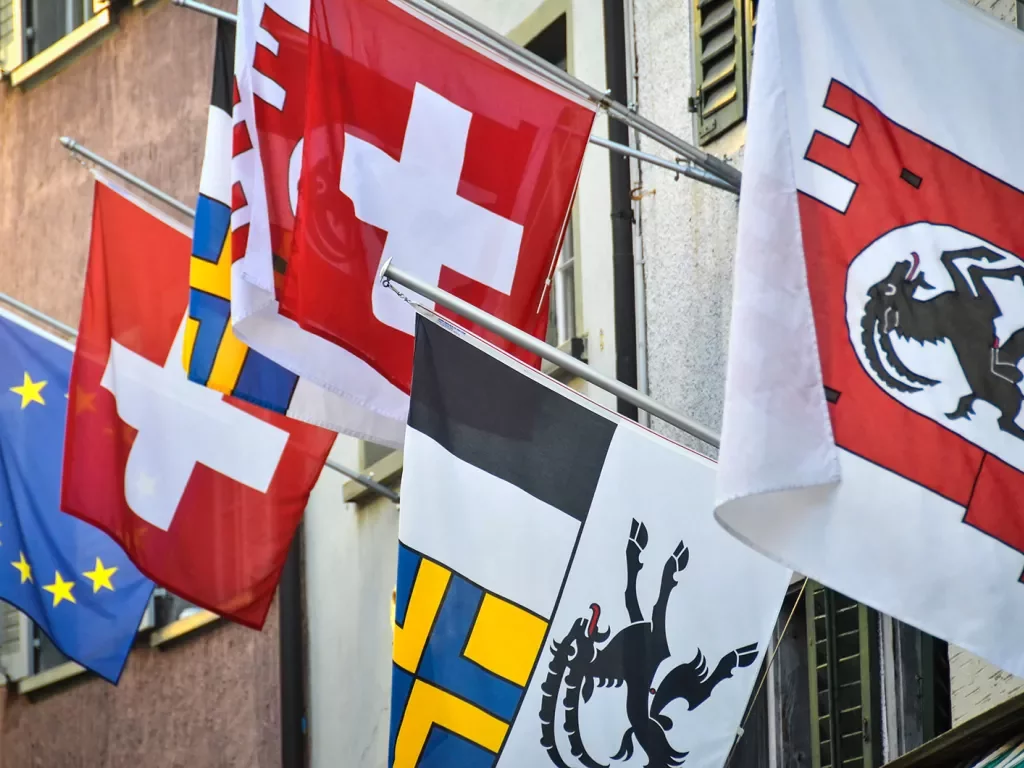 Swiss flags hanging on side of hotel. 