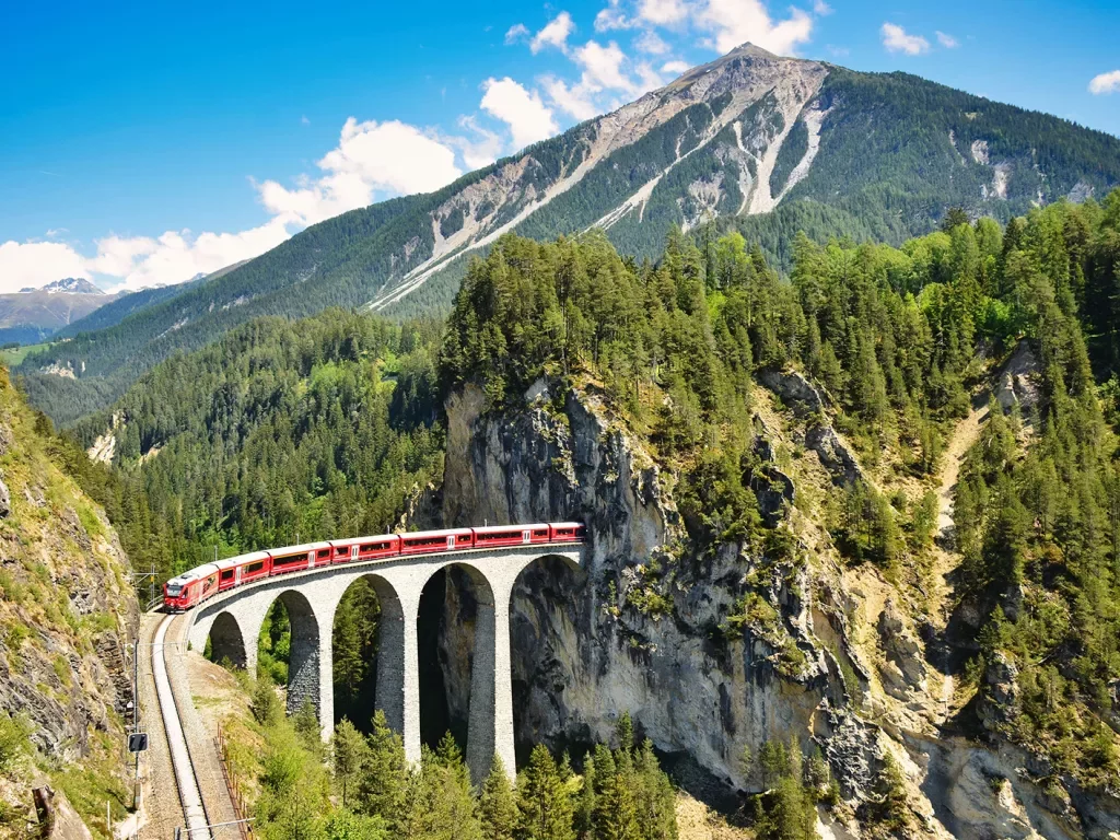 Landwasser viaduct in the Davos mountains near Filisur. Beautiful old stone bridge with a moving train. 