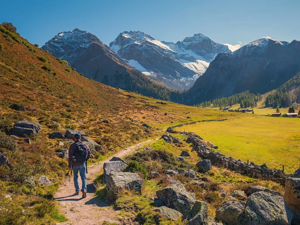 Hiker walking along trail in Swiss Alps.