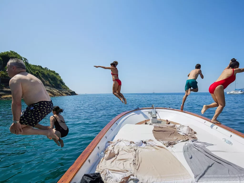 Five guests jumping off boat.