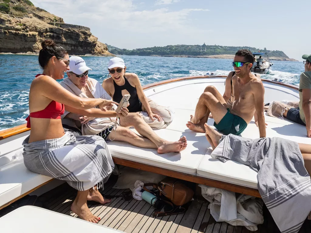 Six guests on boat, three looking at one of their phones.