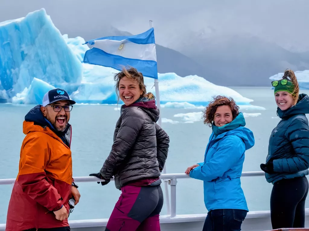 Four guests looking towards camera, blue glaciers behind them.