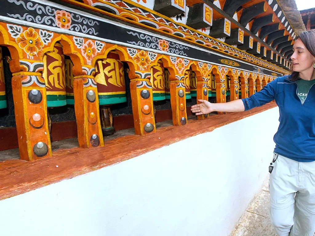 Woman running her hand over prayer wheels in Bhutan