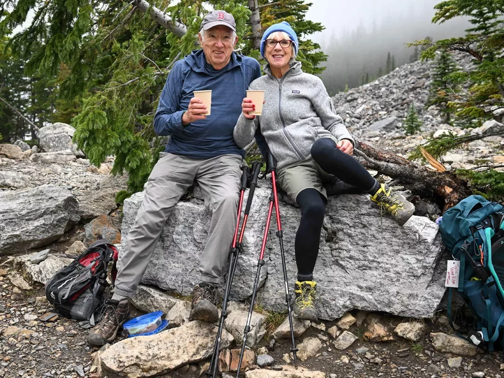 Two guests relaxing on rock, beverages in hand.