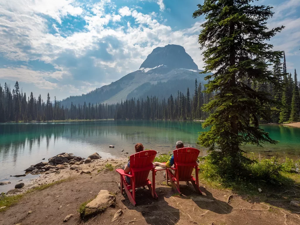 Two guests sitting lakeside, Wapta Mountain in distance.