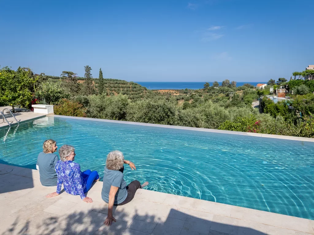 Three women resting by a hotel pool in Greece.
