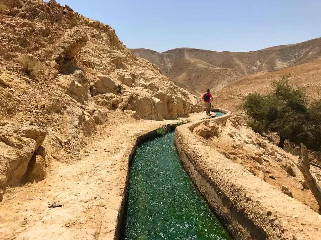 Hiker walking along irrigation system in Oman