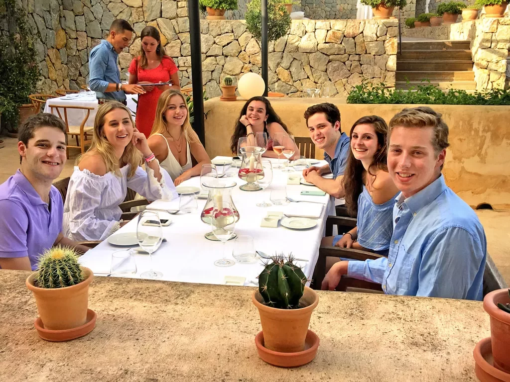 Group of young guests at dinner table, smiling at camera.