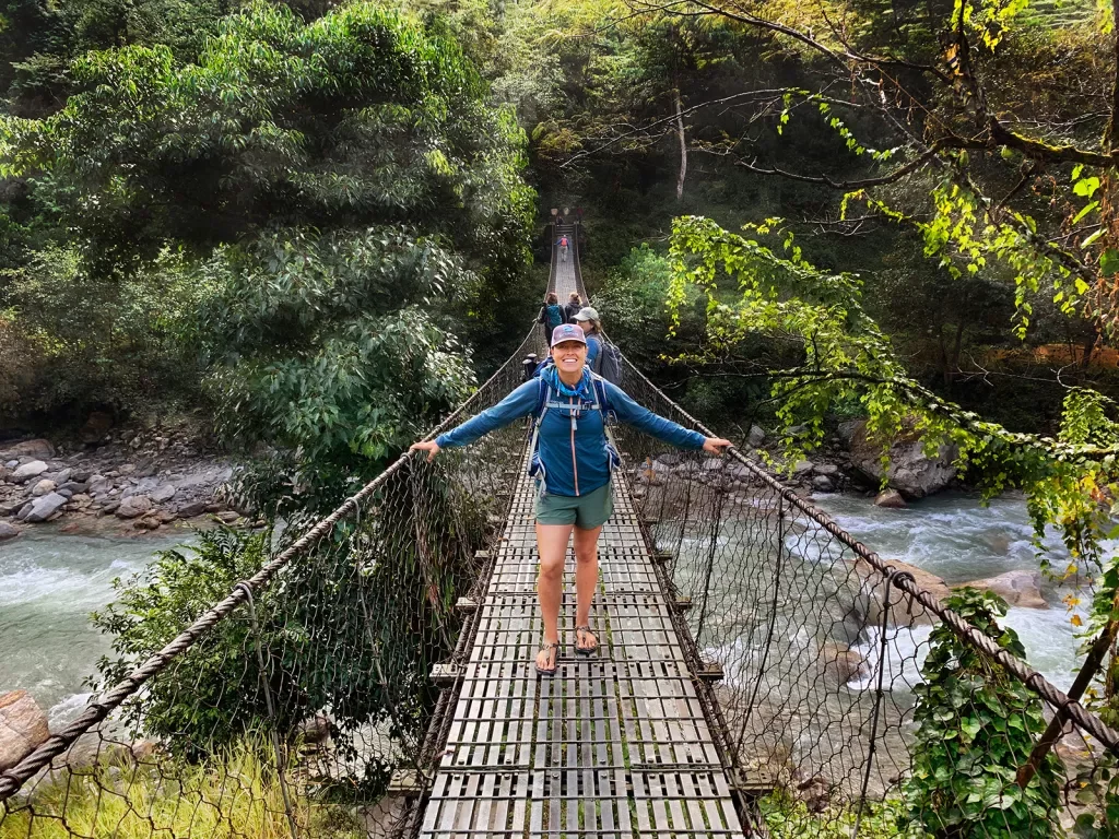 Hiker standing on a bridge over a river in Nepal