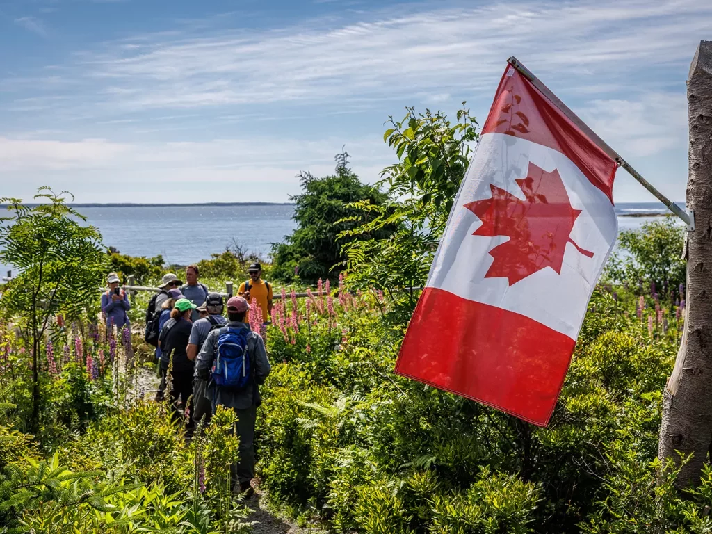 Guests in coastal garden, Canadian flag in foreground.