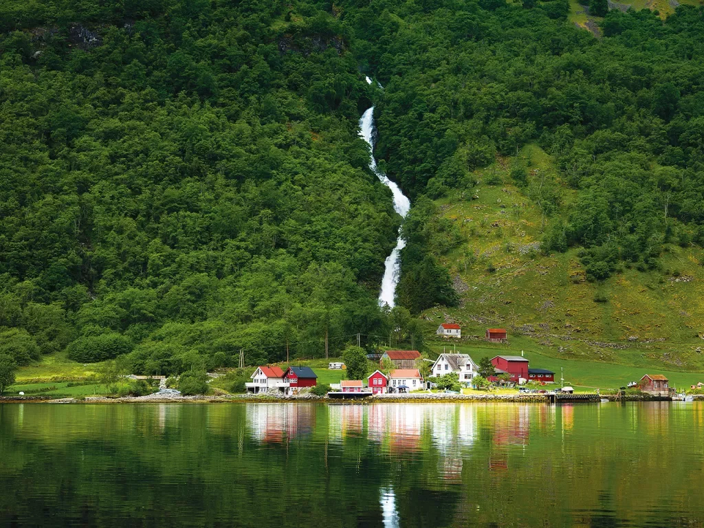Waterfall cascading down a green grassy hill in Norway