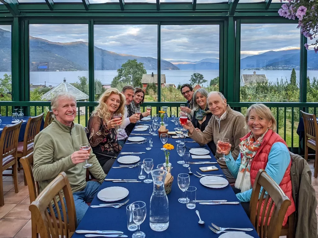 Group of hikers enjoying a meal together while overlooking a fjord and mountains