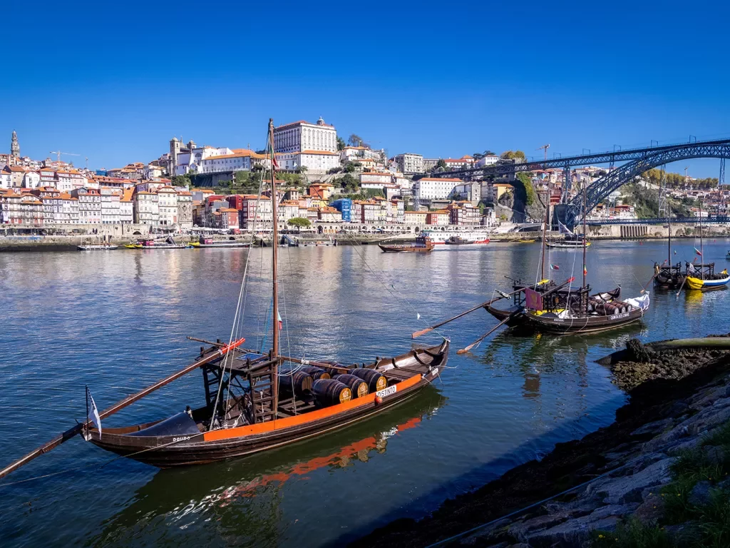Shot of Porto river, boats, riverside houses, bridge in distance. 