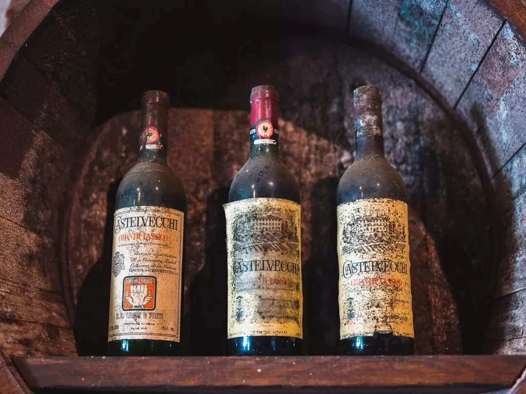 Three very old, dust covered bottles of red wine.